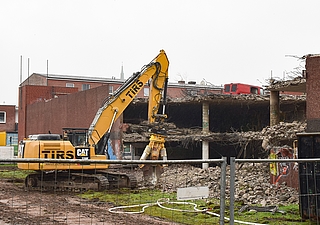 Ein Bagger reißt das Parkhaus am Wedenkamp ab. Kurios: Auf dem oberen Deck steht noch ein roter Transporter. Mindestens eine Fensterscheibe des Wagens ist eingeschlagen. (Foto: Frank)